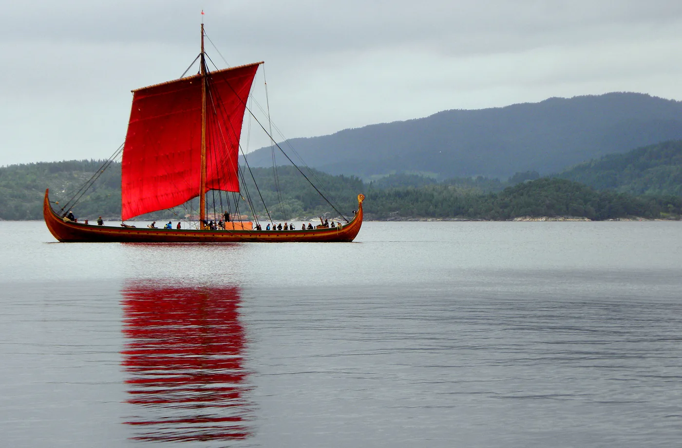 Draken Harald Hårfagre under a red square sail on the Osterfjord, mirrored in still water